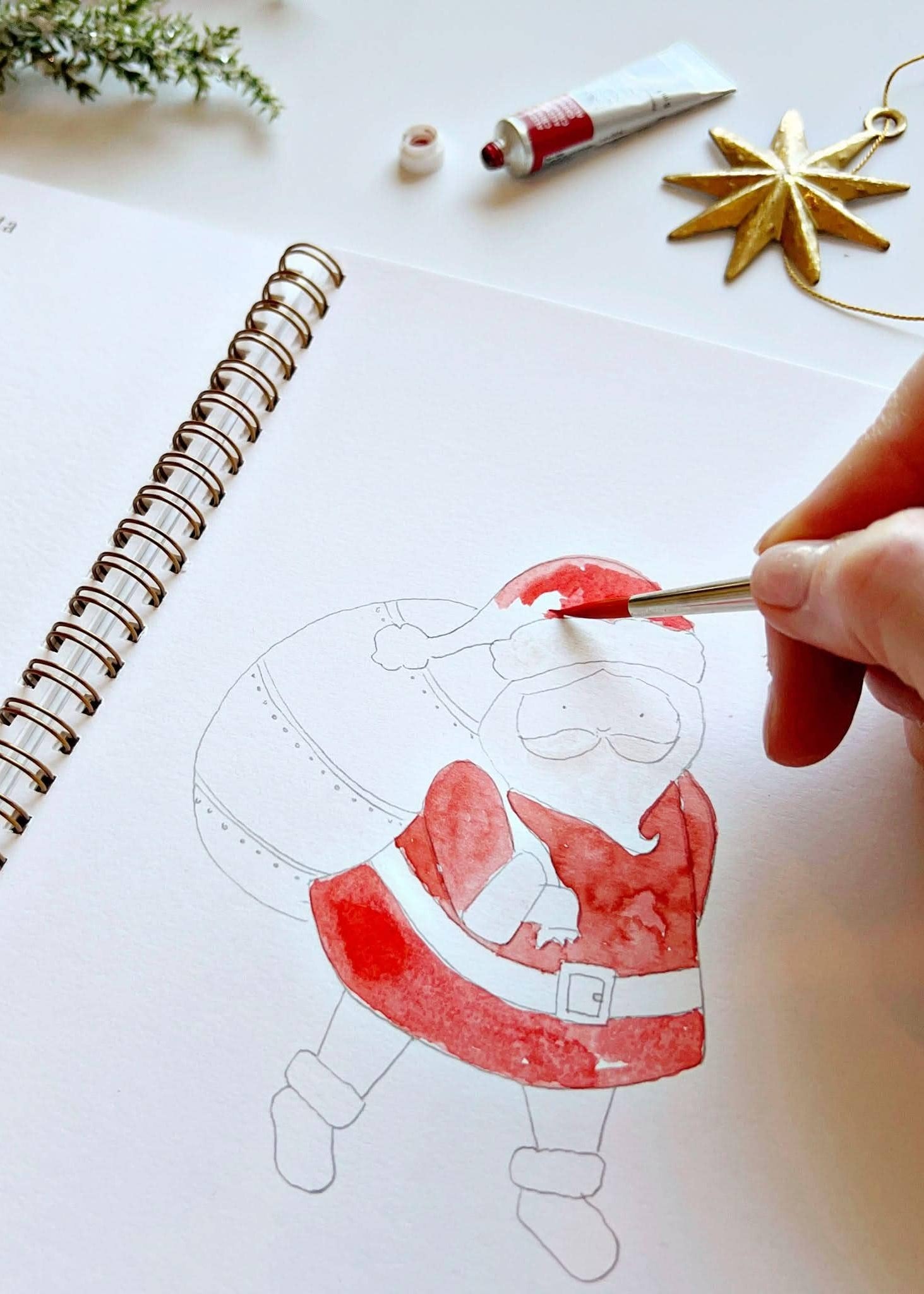 Image of someone painting a design of Santa in the Christmas watercolor workbook.