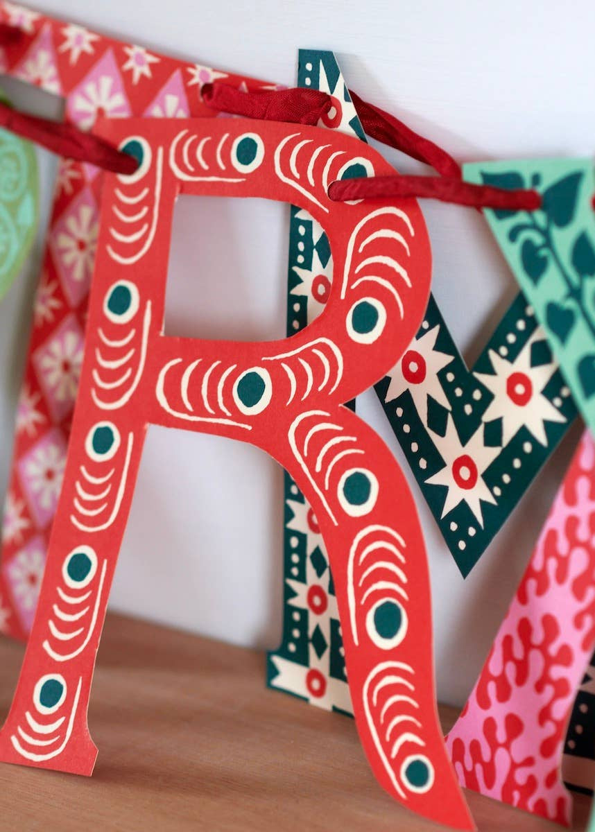 A close up photo of the Merry Christmas banner showing detailed art on each letter.