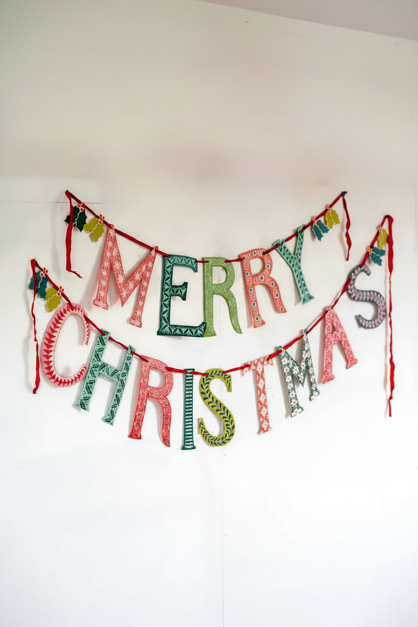 A festive display of the Merry Christmas Garland strung on red ribbon in two tiers, with “Merry” on the top and “Christmas” below.