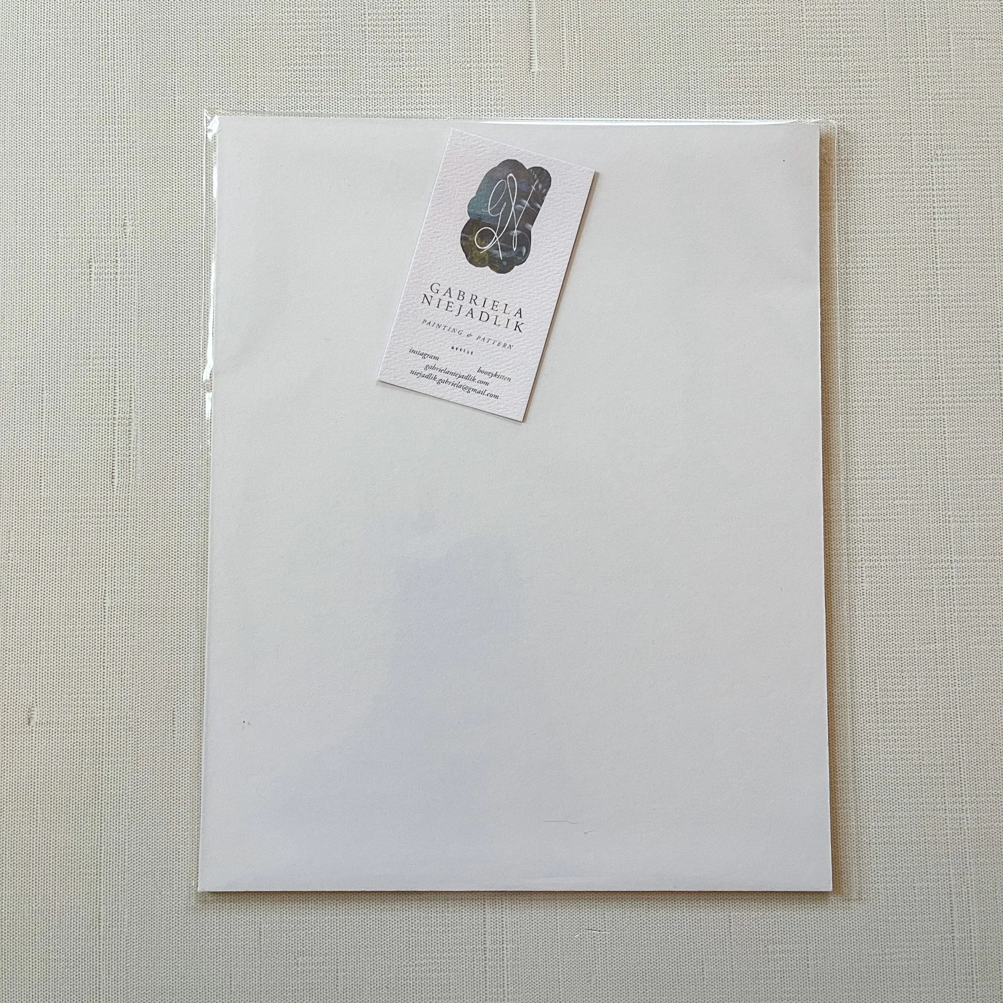 White envelope with a matching card on a textured beige background