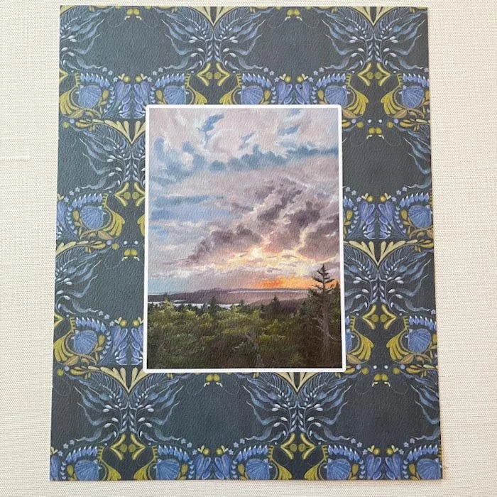 Decorative paper with a landscape painting inset on a patterned background
