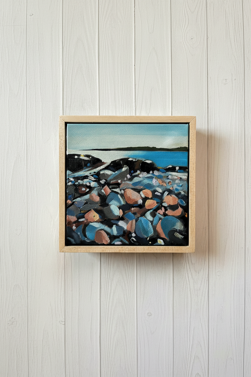 Framed painting of a rocky shoreline with a body of water.
