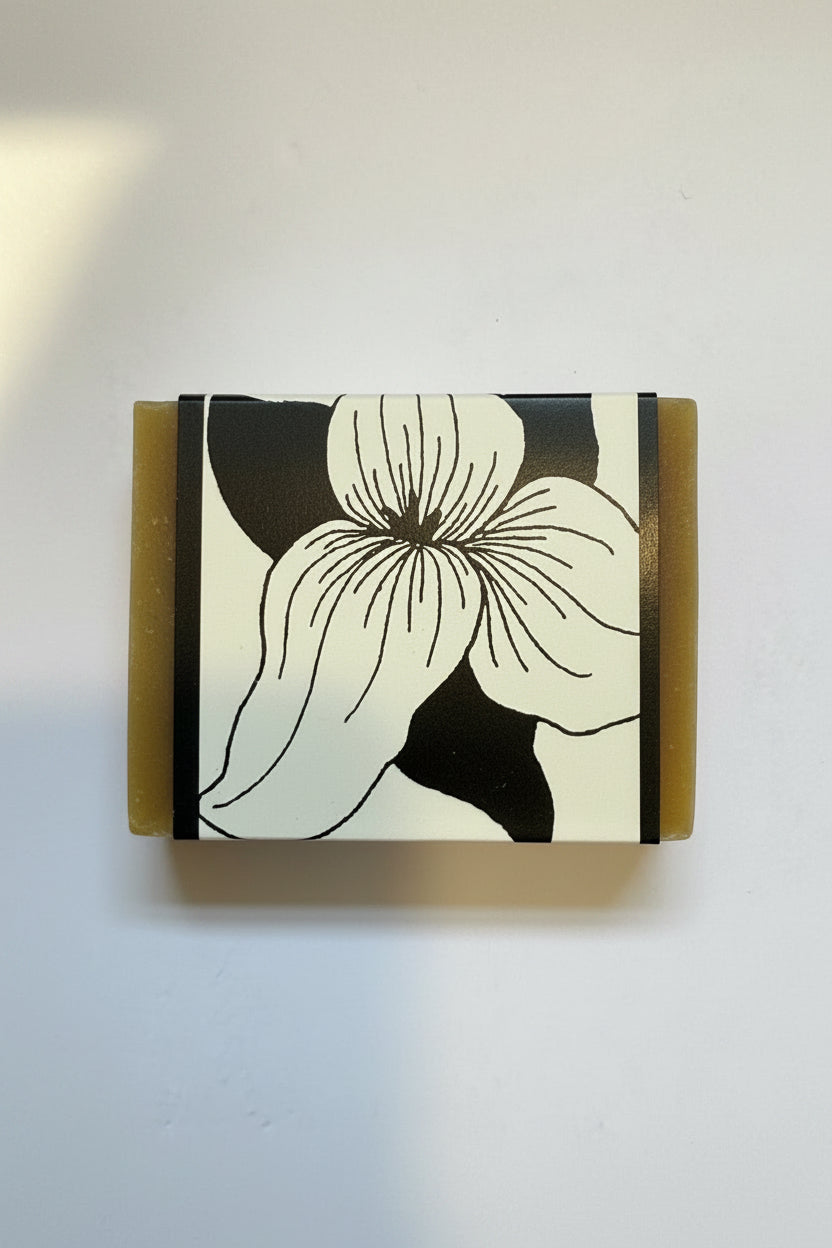 A rectangular bar of soap with a black and white floral design on the front, set against a plain off-white background.
