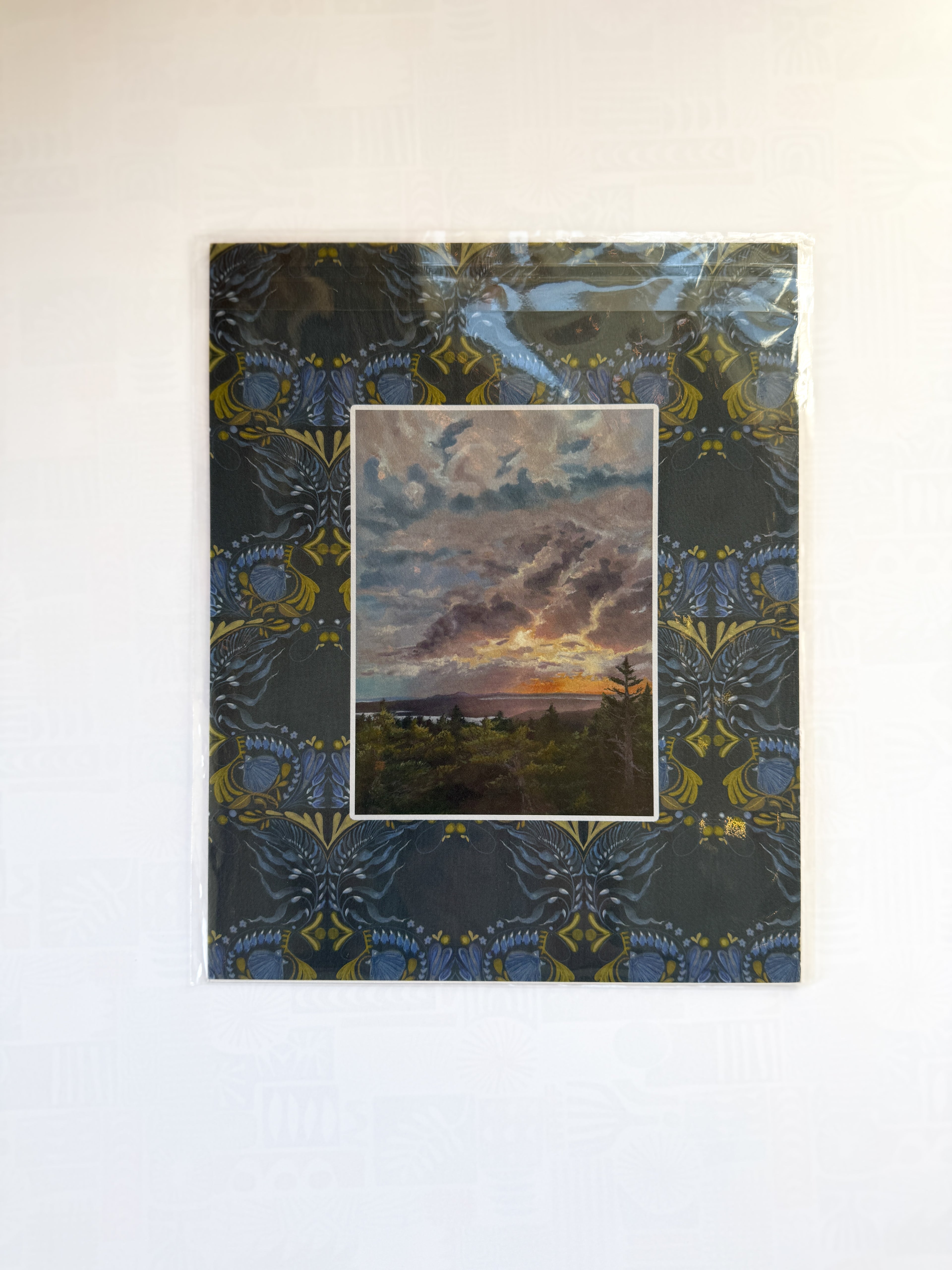 Decorative paper with a landscape print and ornate border on a plain background