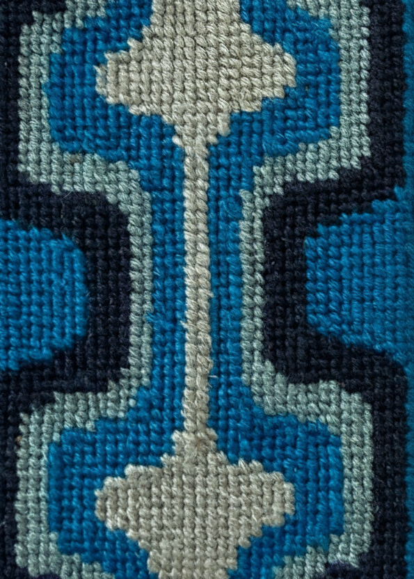 Close-up of a cross-stitched design with blue and gray floral patterns.
