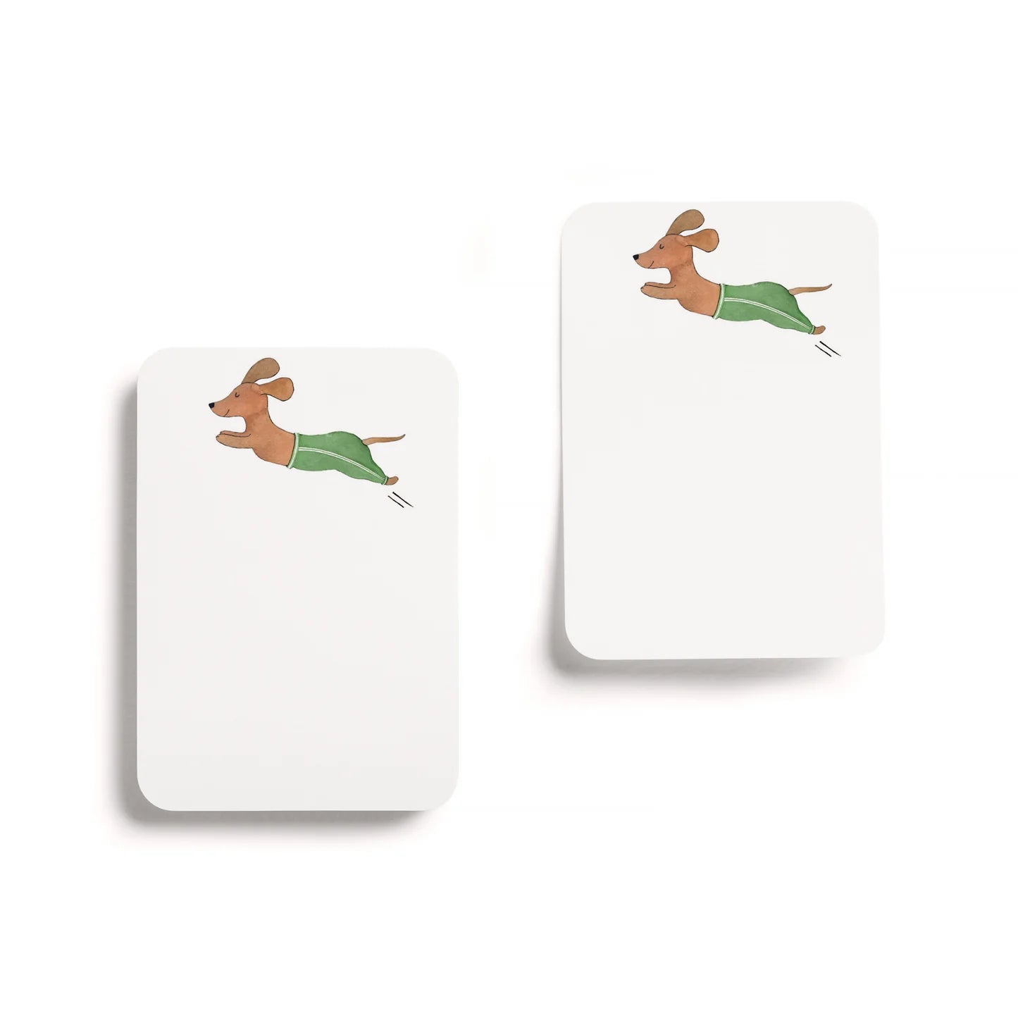 Two white notepads with cartoon dachshunds on a white background