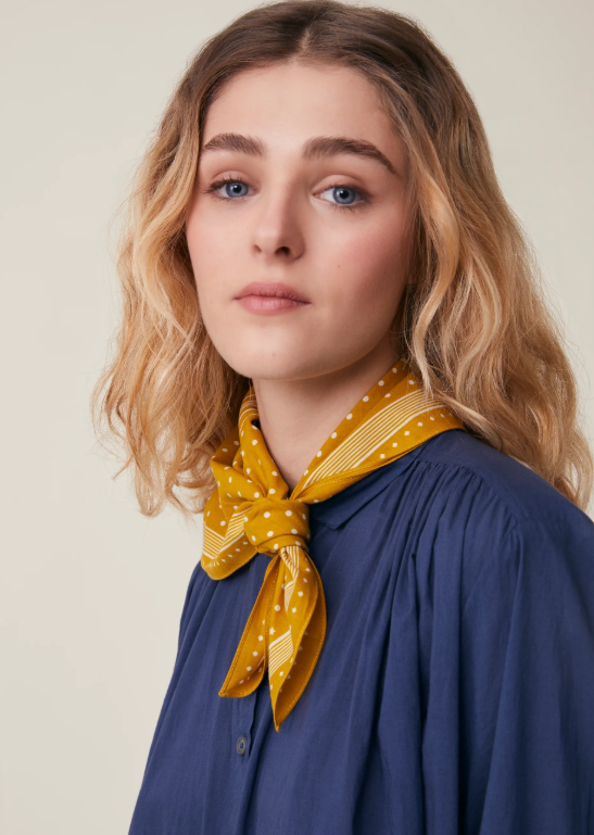 Model wearing Allegra N'843 Moismont Scarf in Farandole yellow as a neckerchief.