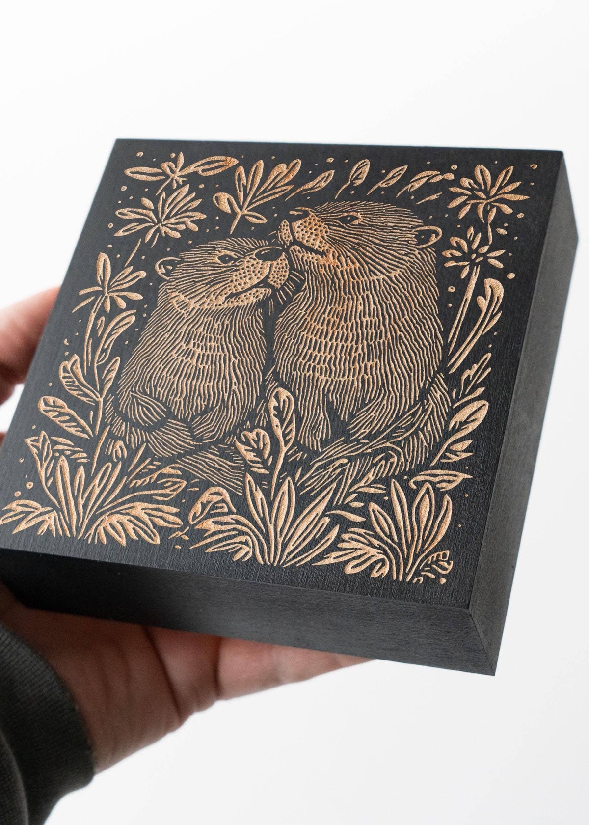 A person holding the Otters Engraved Birch Wood Panel.