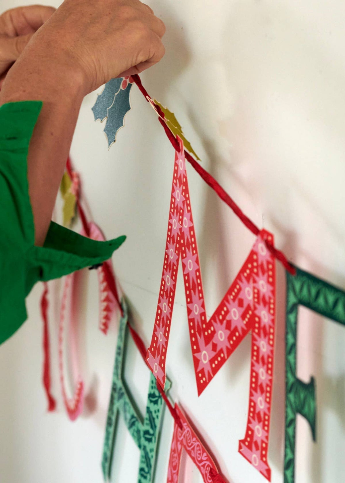 Photo of a woman hanging the Merry Christmas banner.