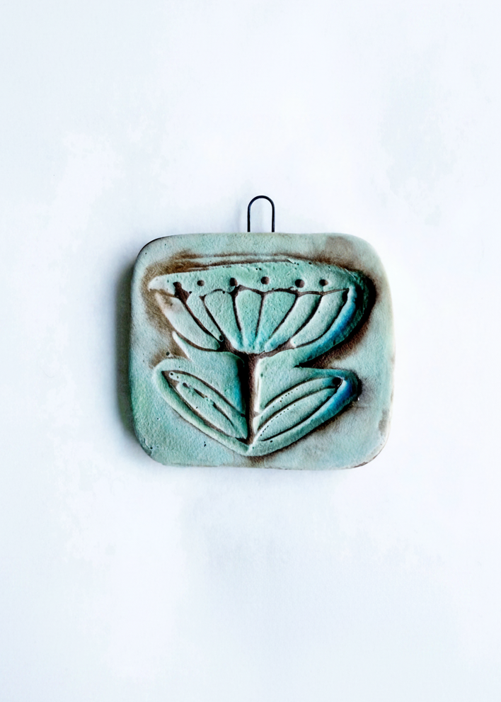 Wall tile with Buttercup design in turquoise finish.